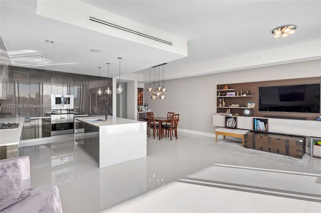 kitchen with an island with sink, light tile patterned floors, pendant lighting, and sink