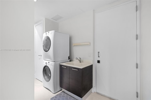 washroom with light tile patterned floors, stacked washer and clothes dryer, and sink