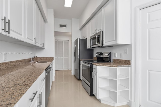 kitchen with sink, stainless steel appliances, dark stone countertops, and white cabinetry