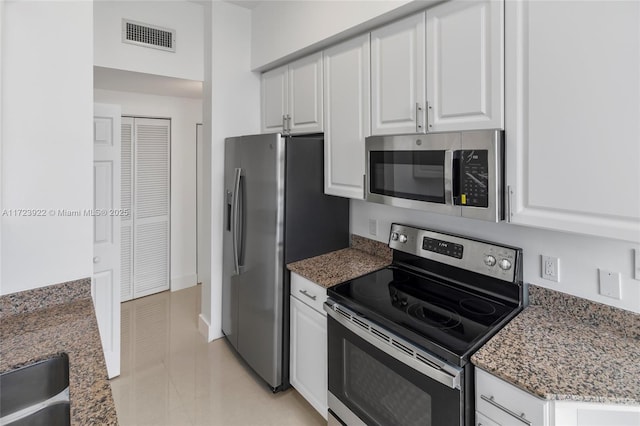 kitchen featuring dark stone counters, stainless steel appliances, white cabinetry, and sink