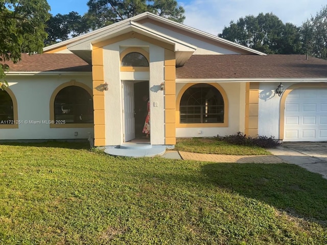 view of front facade with stucco siding, an attached garage, a front yard, and roof with shingles