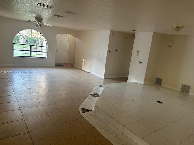 spare room with a ceiling fan, light tile patterned floors, arched walkways, and visible vents