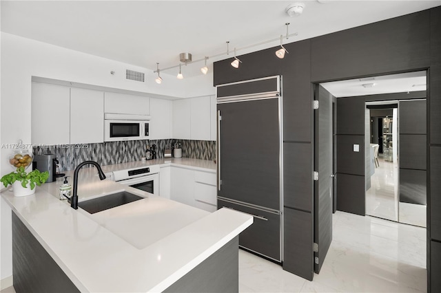 kitchen featuring tasteful backsplash, oven, sink, white cabinets, and paneled built in refrigerator