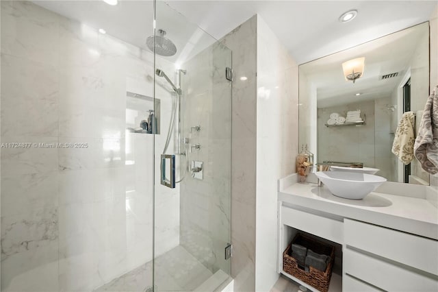 bathroom featuring a shower with shower door and vanity