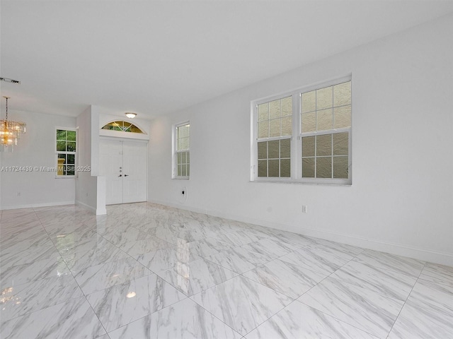 unfurnished room featuring a chandelier