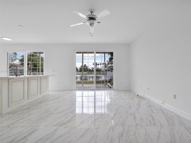 unfurnished room featuring ceiling fan and a water view