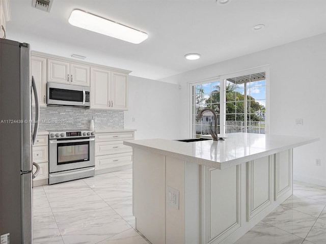 kitchen featuring sink, a center island with sink, tasteful backsplash, and appliances with stainless steel finishes