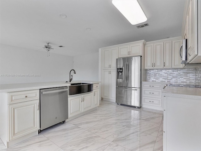 kitchen with appliances with stainless steel finishes, ceiling fan, decorative backsplash, and sink