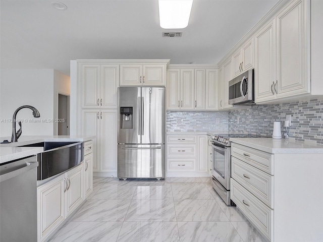 kitchen with white cabinets, appliances with stainless steel finishes, decorative backsplash, and sink