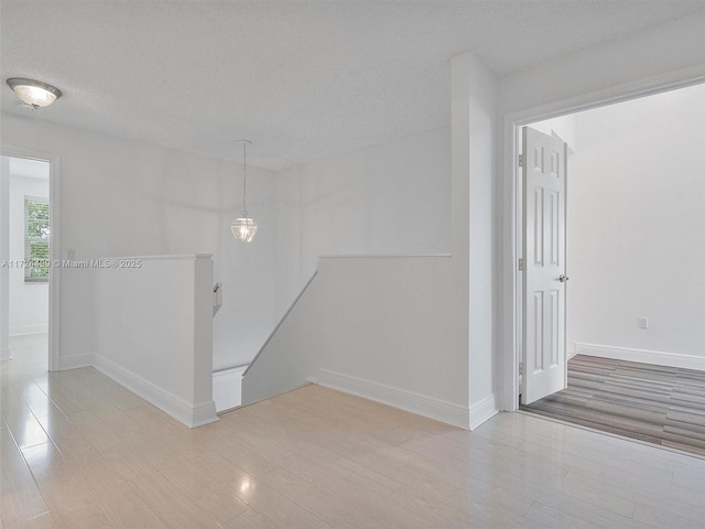 hall with a textured ceiling and light hardwood / wood-style floors