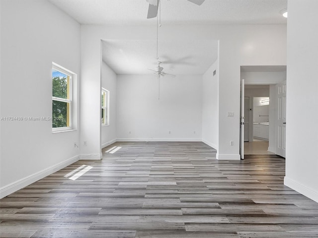 spare room with a textured ceiling, ceiling fan, and light hardwood / wood-style flooring