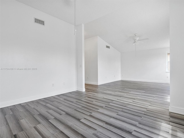 empty room with vaulted ceiling, ceiling fan, and light hardwood / wood-style floors