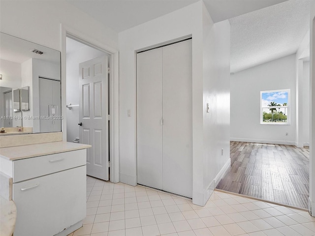 bathroom with a textured ceiling, lofted ceiling, and tile patterned floors