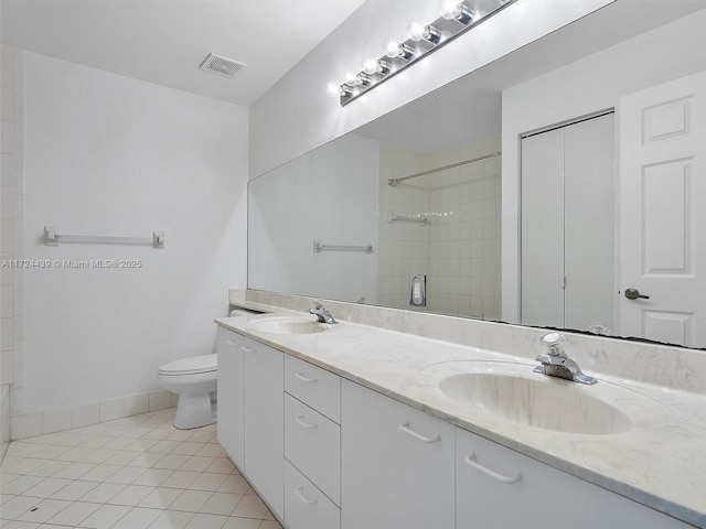 bathroom featuring toilet, a tile shower, vanity, and tile patterned floors