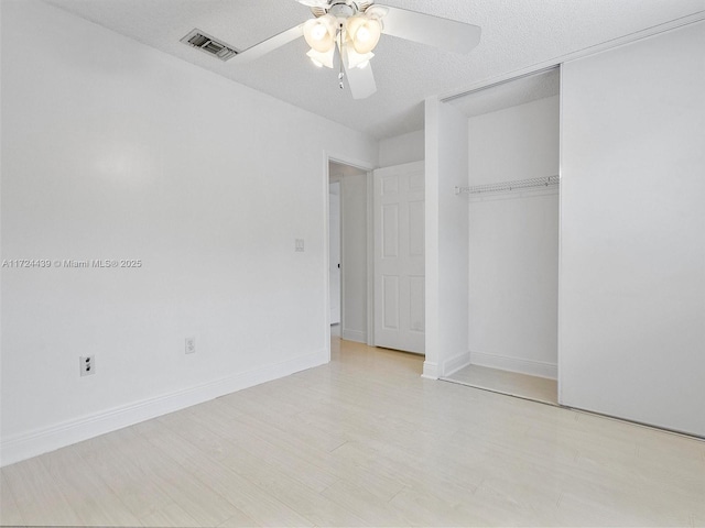 unfurnished bedroom with a textured ceiling, ceiling fan, and a closet