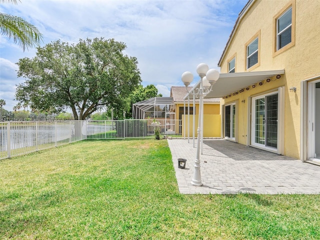 view of yard featuring a patio area, a lanai, and a water view