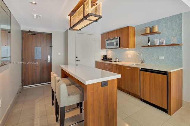 kitchen featuring dishwasher, a breakfast bar, a kitchen island, backsplash, and sink