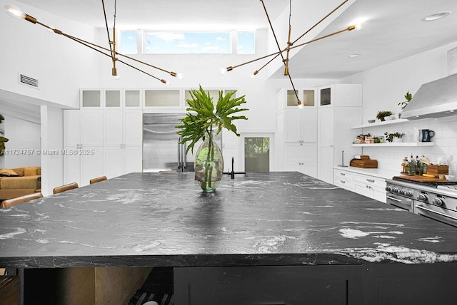 kitchen with dark stone counters, white cabinets, a large island, and decorative backsplash