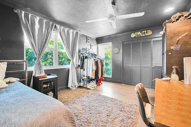 bedroom featuring hardwood / wood-style flooring, a textured ceiling, a closet, crown molding, and ceiling fan