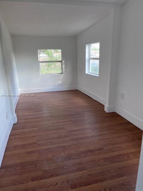 empty room with dark hardwood / wood-style flooring and a wealth of natural light