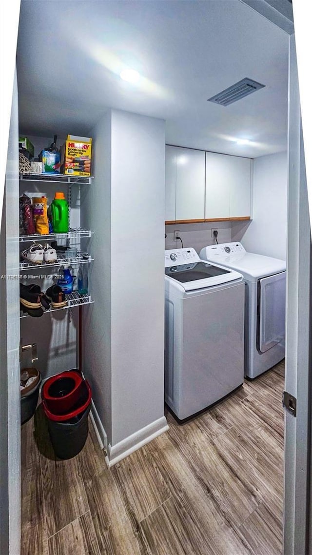 laundry room with cabinets, washing machine and clothes dryer, and light hardwood / wood-style floors