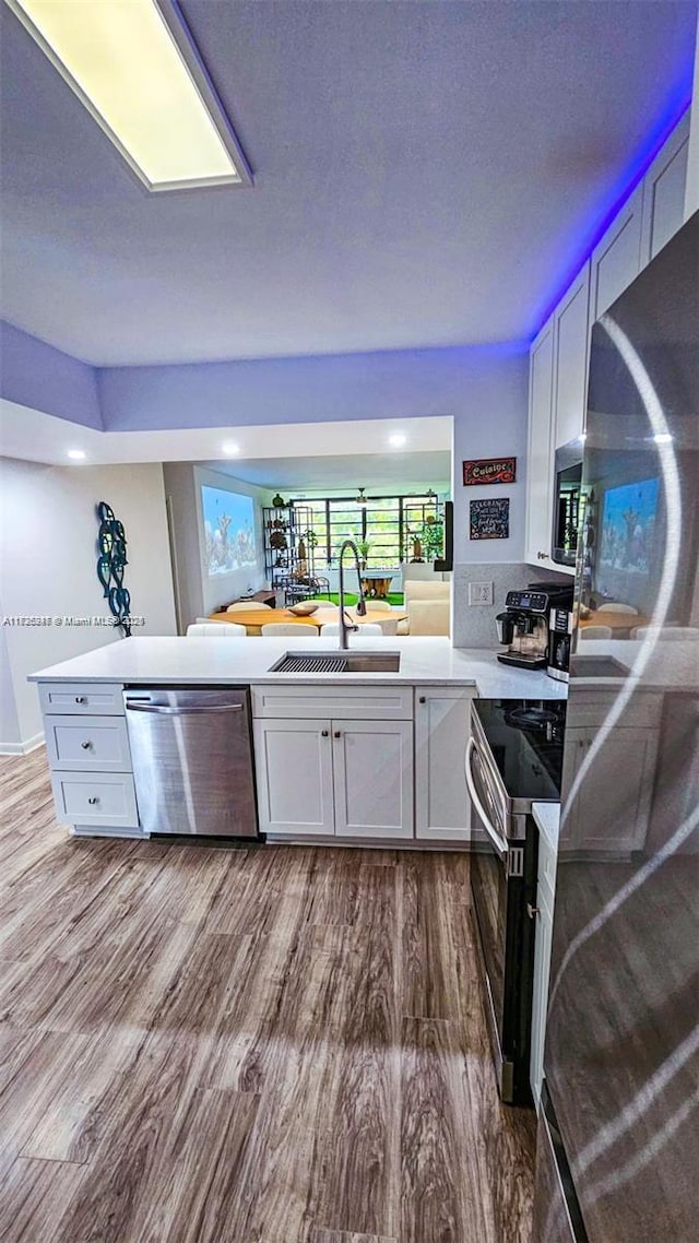 bar featuring sink, white cabinetry, and appliances with stainless steel finishes