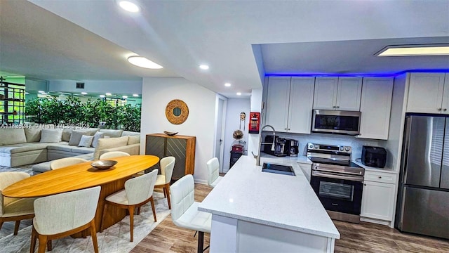 kitchen with light stone countertops, stainless steel appliances, hardwood / wood-style floors, backsplash, and sink