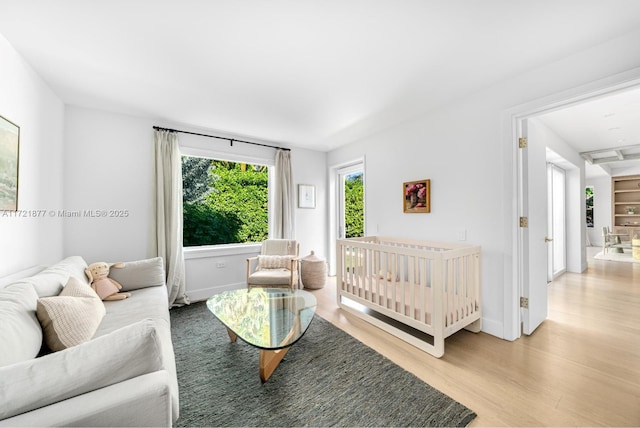 bedroom featuring a nursery area and light wood-type flooring