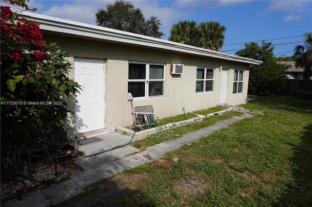 view of property exterior with a lawn and an AC wall unit