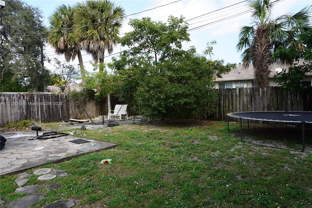 view of yard featuring a patio, a fire pit, and a trampoline