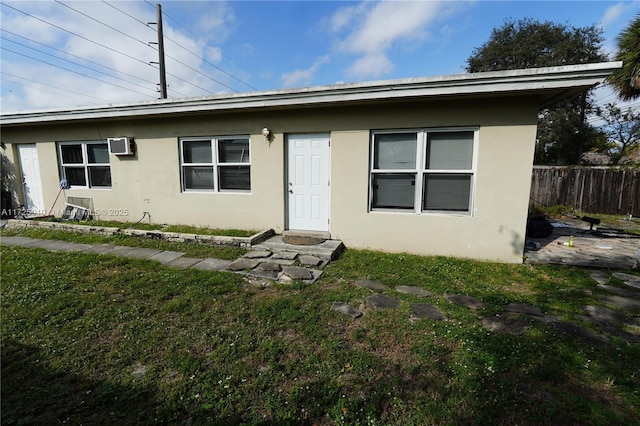 rear view of property featuring a lawn and a wall unit AC