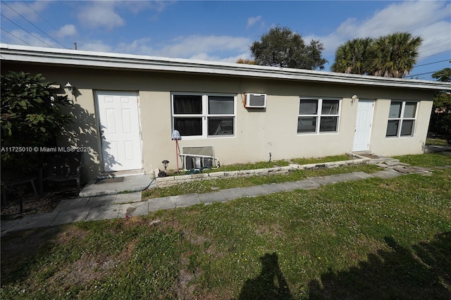 rear view of property featuring a wall mounted air conditioner and a lawn