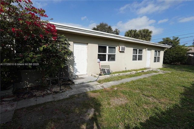 rear view of property featuring an AC wall unit and a yard