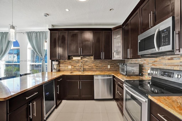 kitchen with dark brown cabinetry, appliances with stainless steel finishes, sink, hanging light fixtures, and light tile patterned floors