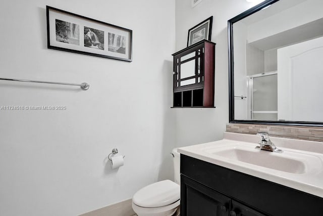 bathroom with toilet, an enclosed shower, and vanity