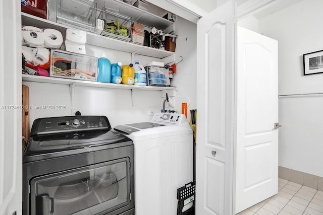 laundry area with light tile patterned floors and washing machine and clothes dryer