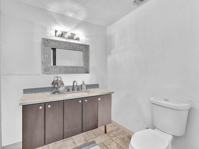 bathroom with a textured ceiling, vanity, and toilet