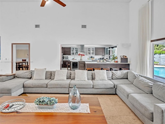 living room featuring a high ceiling, tile patterned flooring, ceiling fan, and wine cooler