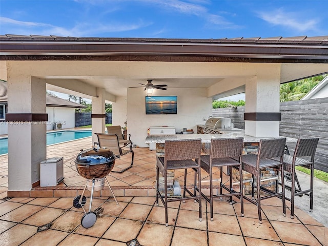 view of patio / terrace featuring grilling area, ceiling fan, exterior bar, area for grilling, and a fenced in pool