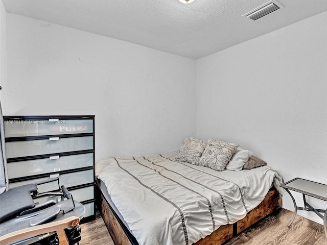 bedroom featuring a textured ceiling and light hardwood / wood-style flooring