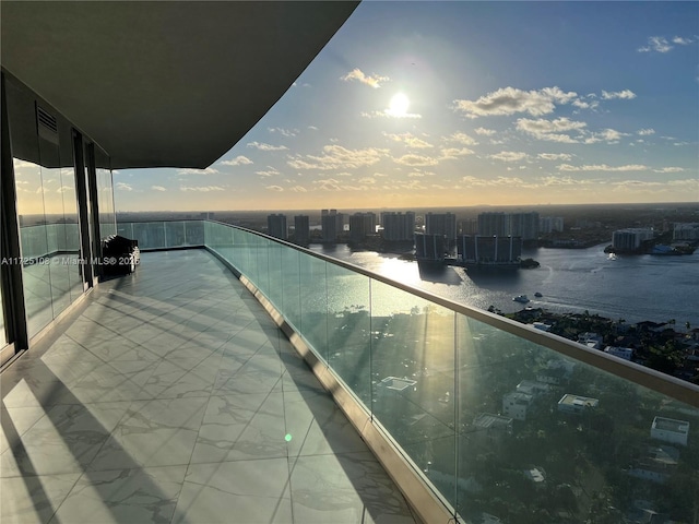 balcony at dusk featuring a water view