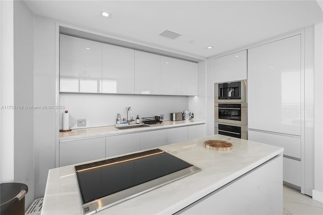 kitchen with light countertops, white cabinetry, a sink, modern cabinets, and black electric cooktop