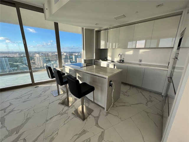 kitchen featuring sink, black electric stovetop, white cabinets, and a center island