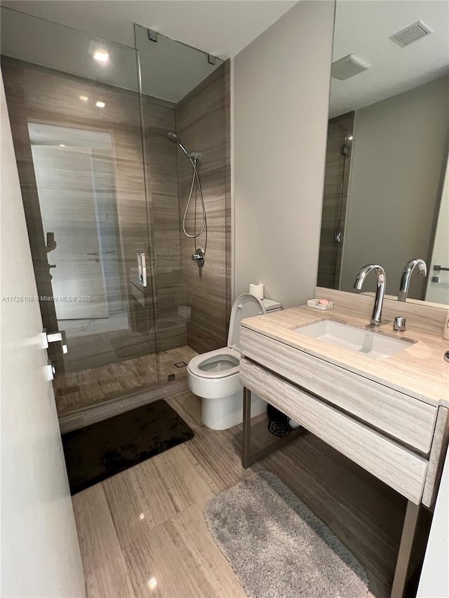 bathroom with an enclosed shower, vanity, and toilet