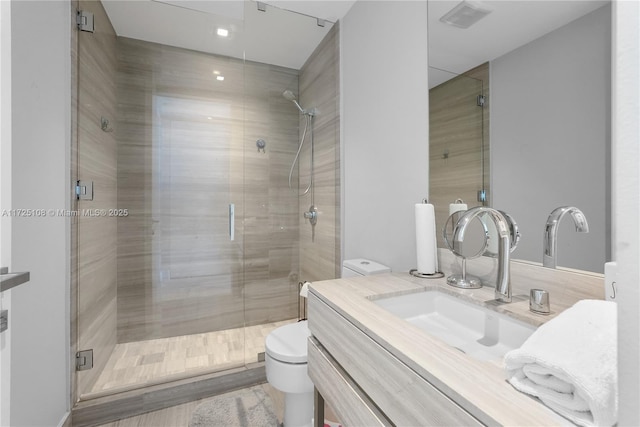 bathroom with toilet, visible vents, a shower stall, and vanity