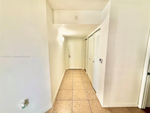 corridor featuring a textured ceiling and light tile patterned floors