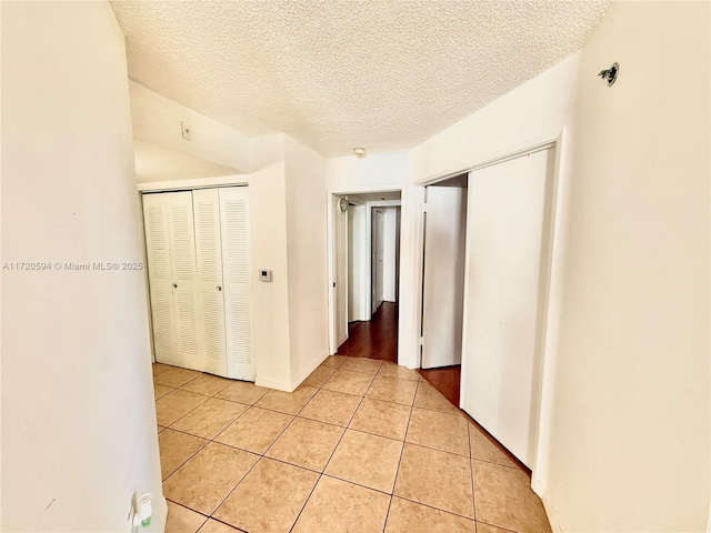 hallway featuring a textured ceiling and light tile patterned floors