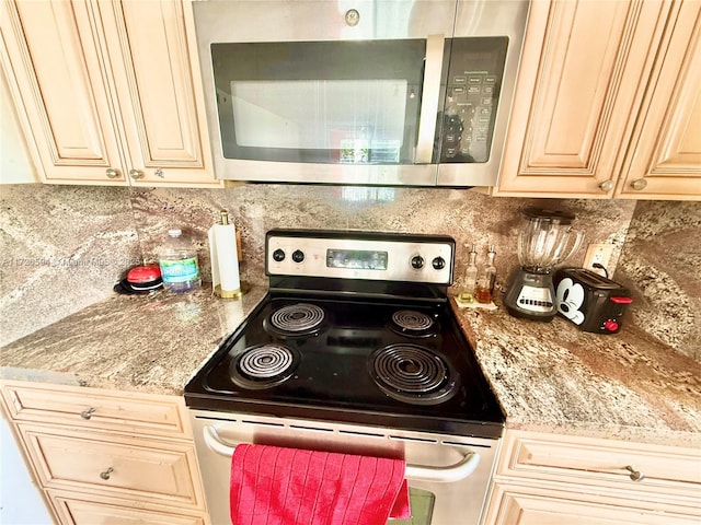 kitchen featuring appliances with stainless steel finishes, cream cabinetry, backsplash, and light stone countertops