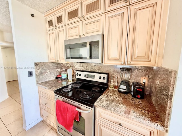 kitchen with light tile patterned floors, appliances with stainless steel finishes, decorative backsplash, and light stone counters