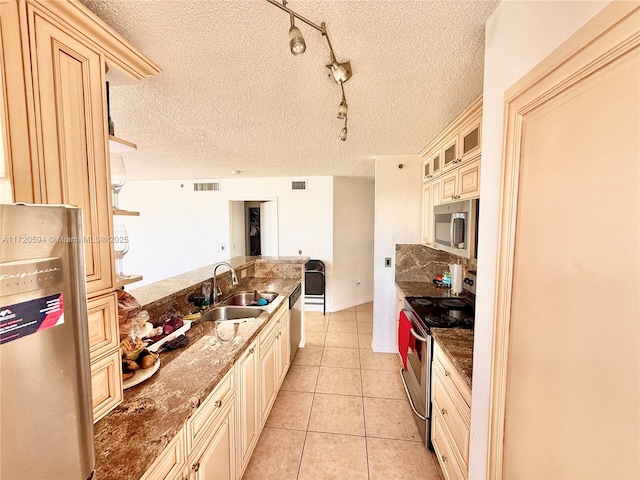 kitchen featuring track lighting, a textured ceiling, sink, and stainless steel appliances